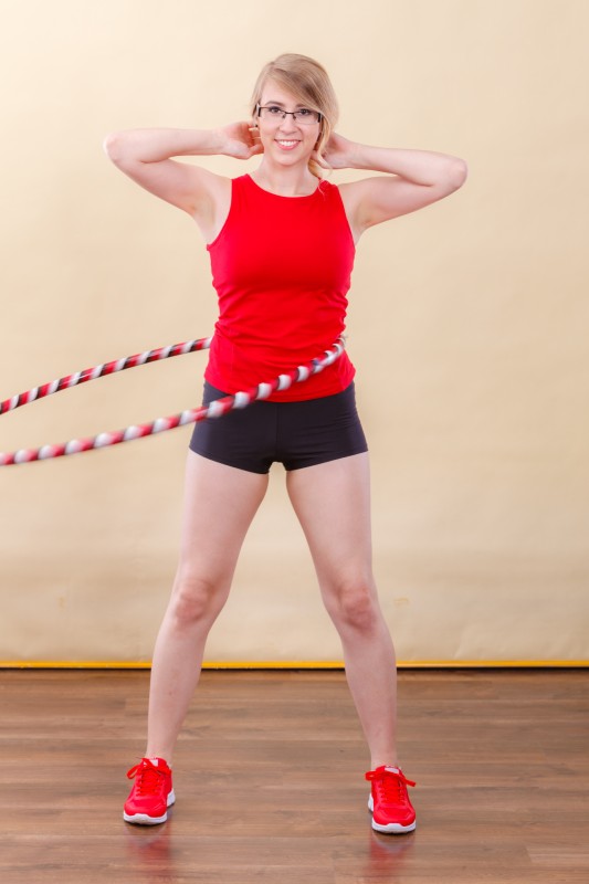 Ganzheitliches Hula-Hoop-Training Sportliche Frau hullert zuhause