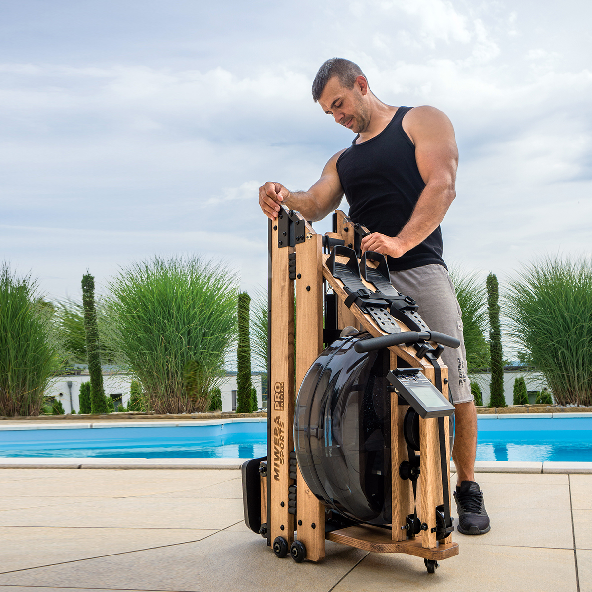 Kompakt und platzsparend Sportler mit einem zusammengeklappten Rudergerät aus Holz