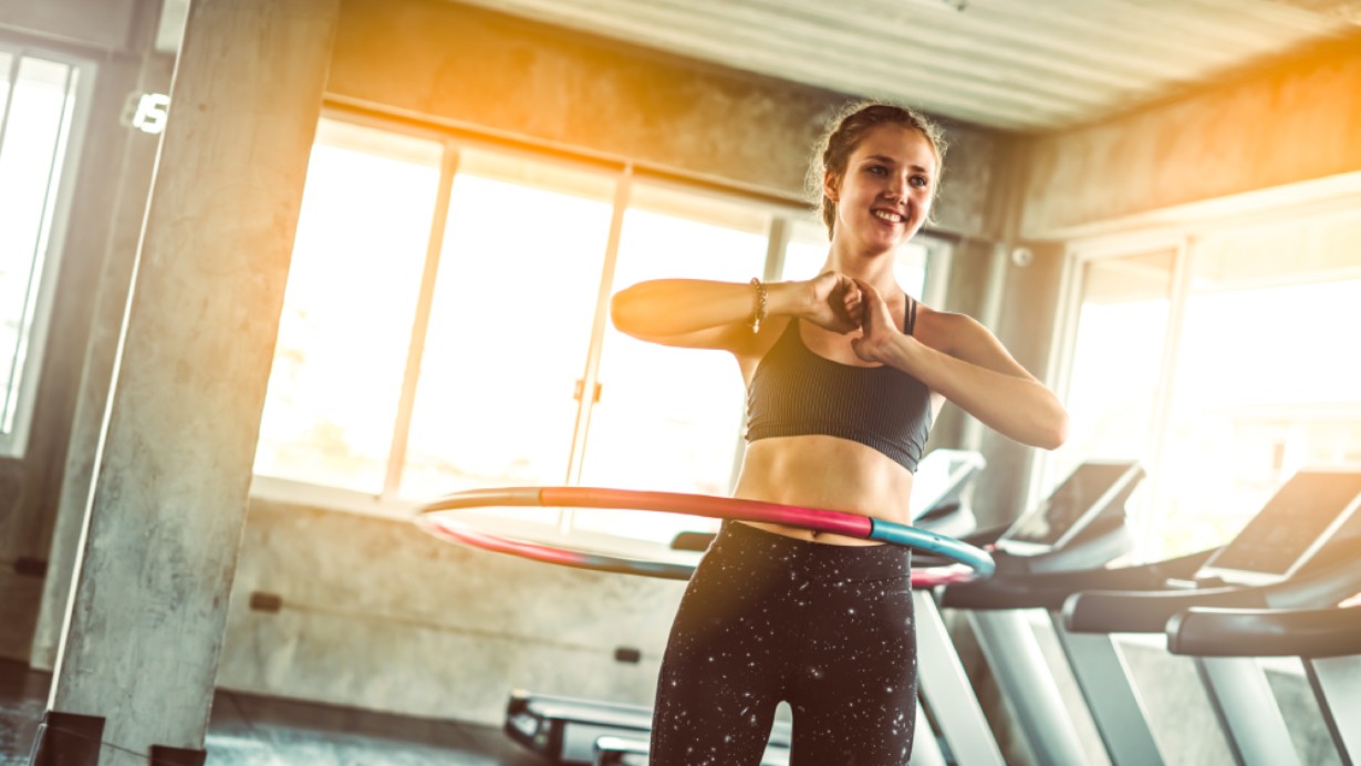 Fit werden mit einem Hula-Hoop-Reifen Im Fitnessstudio mit dem Hulla-Hoop-Reifen aufwärmen